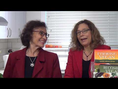 Two women discussing vegan cookbooks in kitchen.