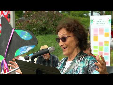 Woman speaking at outdoor Nutrispeak health and nutrition event with colorful banners.