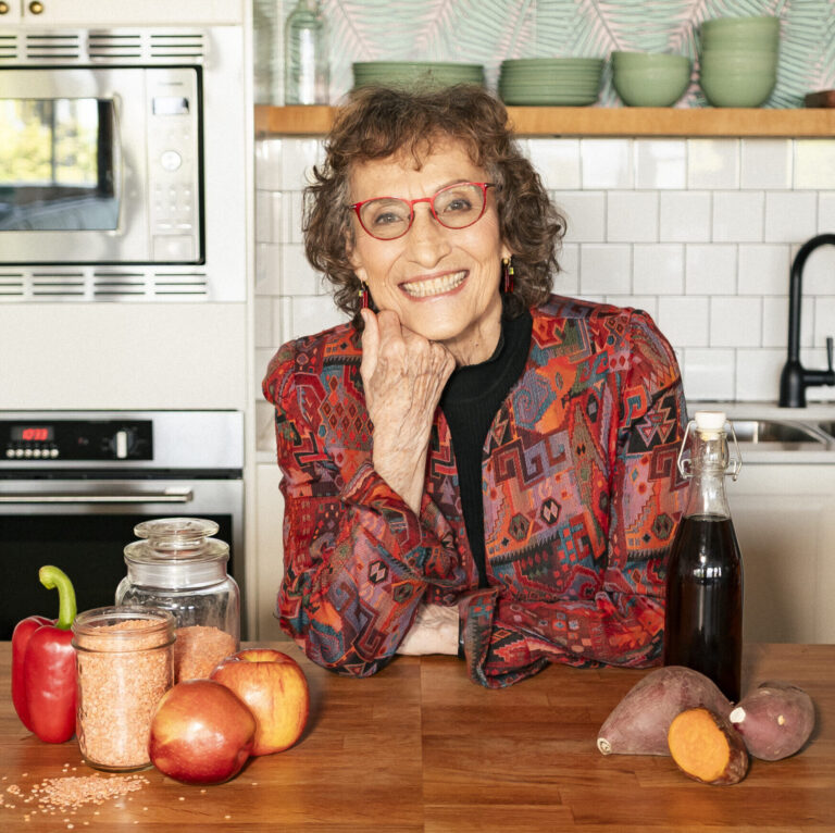 Smiling woman in kitchen with fresh produce.