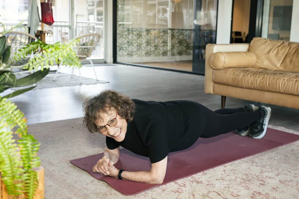 Smiling woman doing yoga on mat in living room
